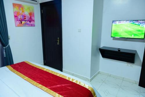 a bedroom with a television and a bed with a red blanket at Cc & Cg Homes Luxury 4-Beds Apart Abuja-24Hrs Power in Abuja