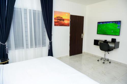 a bedroom with a bed and a desk and a television at Cc & Cg Homes Luxury 4-Beds Apart Abuja-24Hrs Power in Abuja
