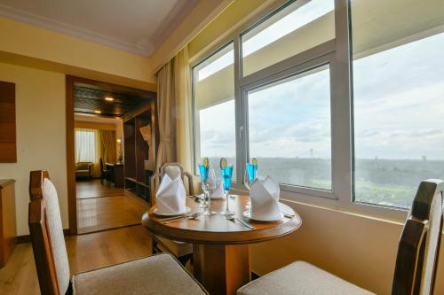 ein Esszimmer mit einem Tisch und einem Fenster in der Unterkunft Peerless Hotel Kolkata in Kalkutta