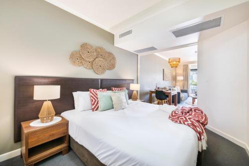 a bedroom with a large white bed and a desk at King Suite Dreams - Poolside Living on the Esplanade in Darwin