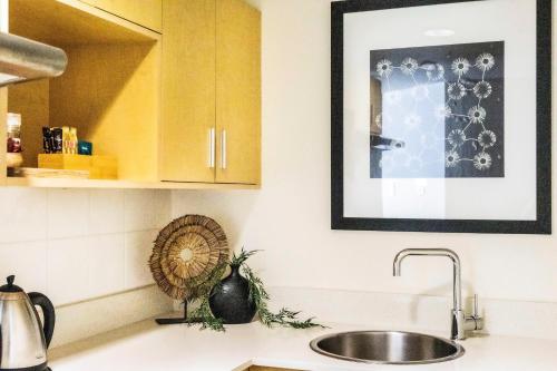 a kitchen with a sink and a picture on the wall at King Suite Dreams - Poolside Living on the Esplanade in Darwin