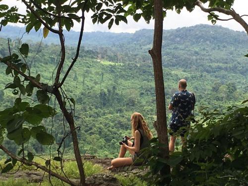 a man and a woman sitting on a hill with a camera at Damnak Tao Meas Homestay in Siem Reap