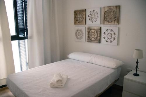 Una cama blanca con toallas en un dormitorio en Céntrico piso para 4 al lado del Jardín Botánico, en Granada