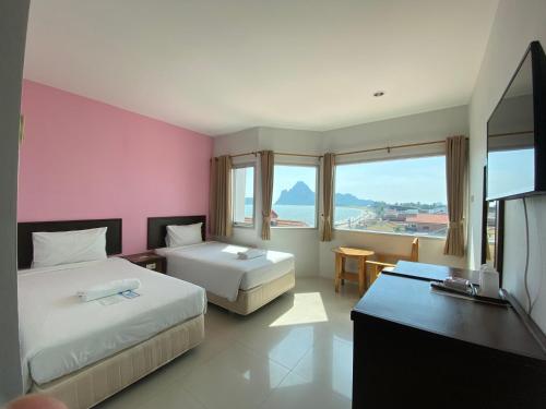 una camera d'albergo con due letti e una televisione di Prachuap Beach Hotel a Prachuap Khiri Khan