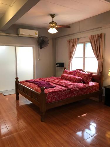 a bedroom with a bed with red sheets and a fan at Apartment kata in Kata Beach