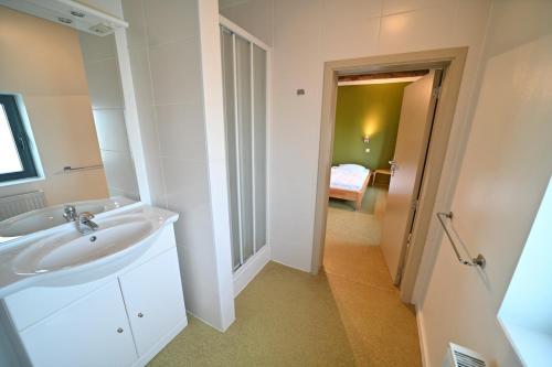 1 dormitorio y baño blanco con lavabo. en Chez Robert, en Petit Han