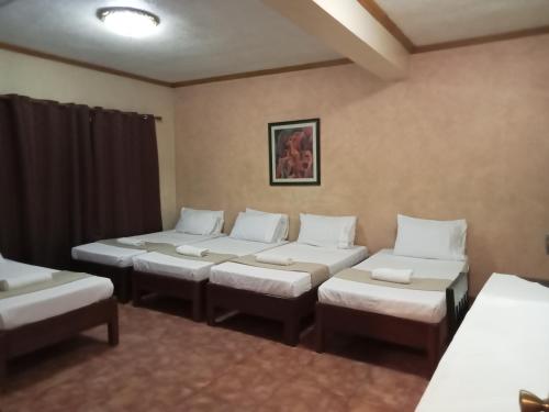 a room with four beds with white pillows at RedDoorz at Casa Marabella Villamonte Bacolod City in Bacolod