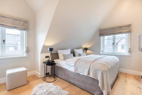 a bedroom with a large bed and two windows at Ferienhaus Finoah - Leben, Luxus, Leichtigkeit hinter der Duene in Westerland Sylt in Westerland (Sylt)