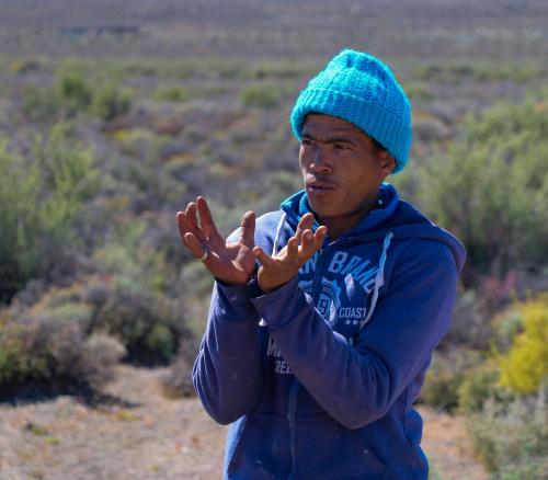a man in a blue hat standing in a field at Oupoort Eco & Guest Farm - Sutherland - Middelpos in Sutherland