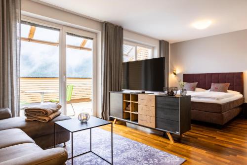 a living room with a couch and a bed and a television at der Sonnberg - Alpinlodges in Zell am See