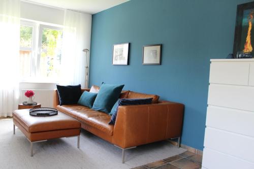 - un salon avec un canapé brun et un mur bleu dans l'établissement Ferienwohnung "Moi Tied" 35222, à Hesel