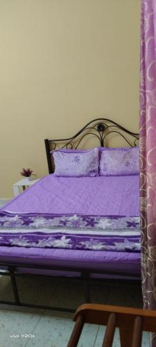 uma cama com lençóis roxos e uma estrutura metálica em HOMESTAY KAKMAH em Jasin