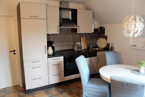 a kitchen with white cabinets and a table with chairs at Ferienwohnung "Moi Tied" 35222 in Hesel