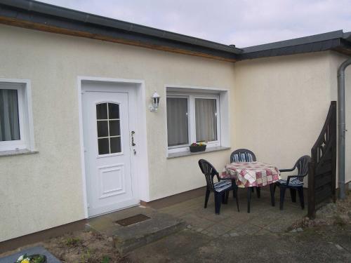 un patio con tavolo e sedie davanti a una casa di Ostsee Bungalow mit Kamin & Terrasse a Ostseebad Koserow
