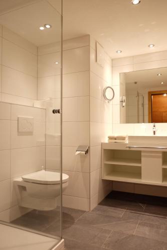 bagno con servizi igienici, lavandino e specchio di Apart Auhof a See