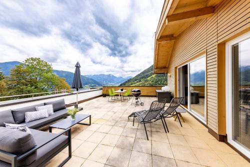 a patio with a couch and chairs on a balcony at der Sonnberg Alpinlodges - Apartments mit Seeblick, privater Sauna und Self Check-In in Zell am See