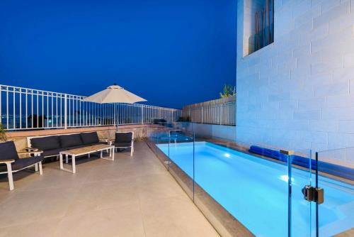 a swimming pool with chairs and a table and an umbrella at לביא אילת lavie eilat in Eilat