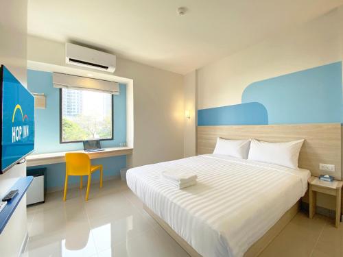 a bedroom with a bed and a desk and a television at Hop Inn Bangkok Onnut Station in Bangkok
