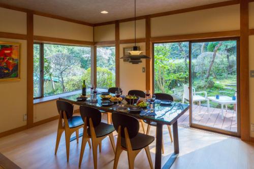 a dining room with a table and chairs and windows at Suite Villa Kamakura Jomyoji in Kamakura
