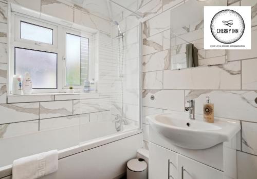 Baño blanco con lavabo y bañera en Large 3 Bedroom House with Parking & Garden by Cherry Inn Short Let's & Services Accomodation, en Cambridge