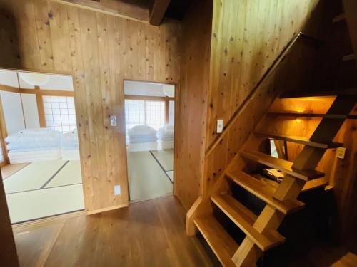 a room with wooden walls and a staircase in a house at Hokyuann - 邦久庵 in Motogoe