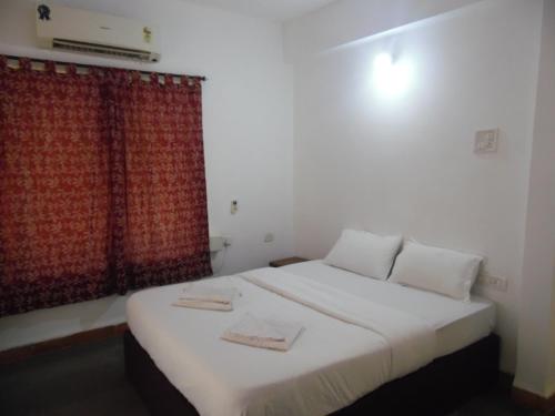 1 dormitorio con cama blanca y cortina roja en Lobos villa en Calangute