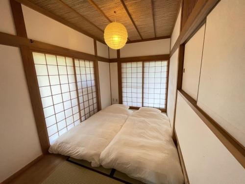 a small bed in a room with two windows at Hokyuann - 邦久庵 in Motogoe