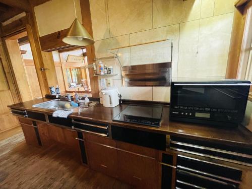 a kitchen with a counter with a microwave and a sink at Hokyuann - 邦久庵 in Motogoe