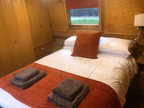 1 dormitorio con 1 cama con toallas en Willow - Cottage on the River, Luxury Houseboat, en Little Baddow