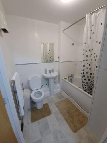 a white bathroom with a toilet and a sink at 2 bedroom flat in SW London in Sutton