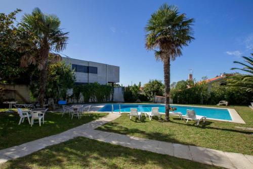 a pool with chairs and a palm tree next to a building at House - 3 Bedrooms with Pool WiFi and Sea views - 7428 in Portonovo