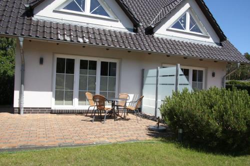un patio con sillas y una mesa frente a una casa en Trassenheide, Ferienidyll Neubauer, en Ostseebad Karlshagen
