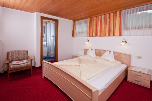 a bedroom with a large bed and a chair at Appartements Wasserfälle in Mayrhofen