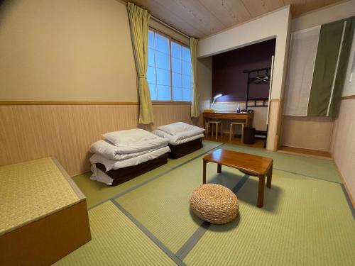 Habitación con 2 camas, mesa y ventana en GuestHouse OC en Fujikawaguchiko