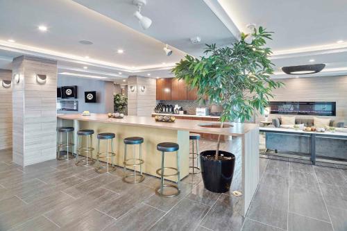 a kitchen with a island with bar stools in it at Sandman Signature Plano-Frisco Hotel in Plano