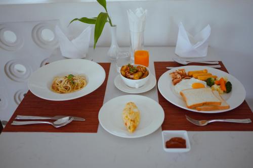a table with plates of breakfast food on it at Montagne Residence in Kampot