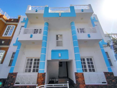 a large white building with blue columns at Sunshine House in Luxor