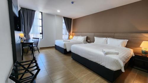 a hotel room with two beds and a desk and a television at Yu Hotel Chinatown in Kuala Lumpur