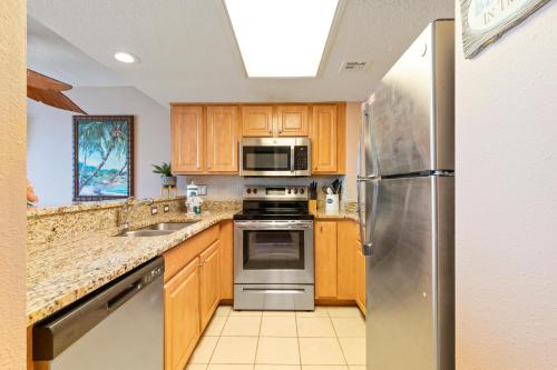 a kitchen with wooden cabinets and stainless steel appliances at Atlantica Towers Condo w Balcony by Hosteeva in Myrtle Beach