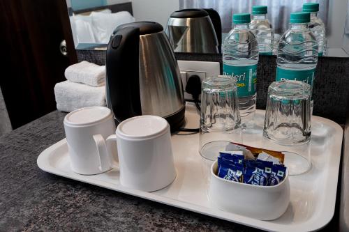 a tray with cups and a coffee maker and water bottles at VALUE INN in Turuvekere