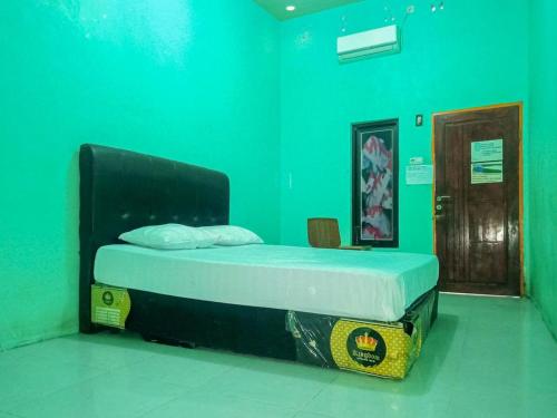 Cama en habitación con pared verde en Wisma Benteng Indah Palopo en Palopo