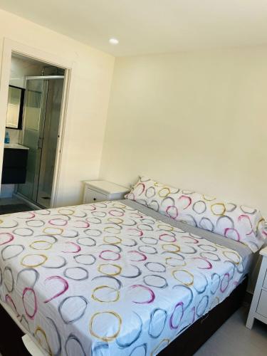 um quarto com uma cama grande e uma colcha branca e rosa em Apartamento Cuidad Ciencias em Valência