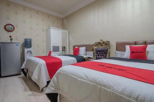 a bedroom with two beds with red and white sheets at RedDoorz Syariah at Jalan Ahmad Yani Jambi in Jambi