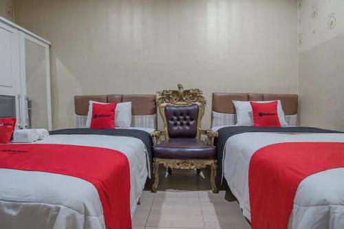 a bedroom with two beds with a chair and red sheets at RedDoorz Syariah at Jalan Ahmad Yani Jambi in Jambi