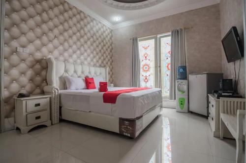 um quarto com uma grande cama branca com almofadas vermelhas em RedDoorz Syariah at Jalan Ahmad Yani Jambi em Jambi