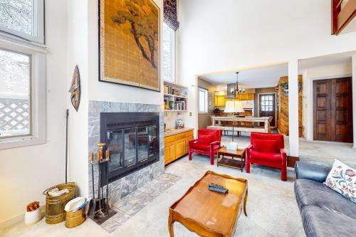 a living room with a fireplace and red chairs at Stone Creek Lodge in Avon