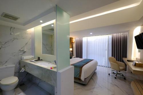 a hotel room with a bed and a bathroom at Dream of Aventus Hotel Kuta in Kuta