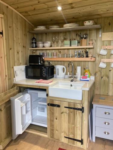 een keuken met een wastafel en een koelkast bij The Dragon's Hut with pool now open in Wrexham