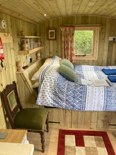 a bedroom with a bed and a chair in a room at The Dragon's Hut with cozy logburner in Wrexham