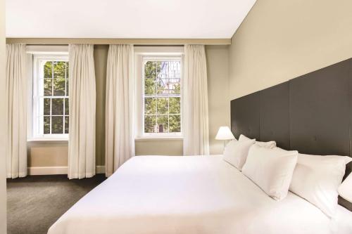 a bedroom with a large white bed with two windows at Adina Apartment Hotel Adelaide Treasury in Adelaide